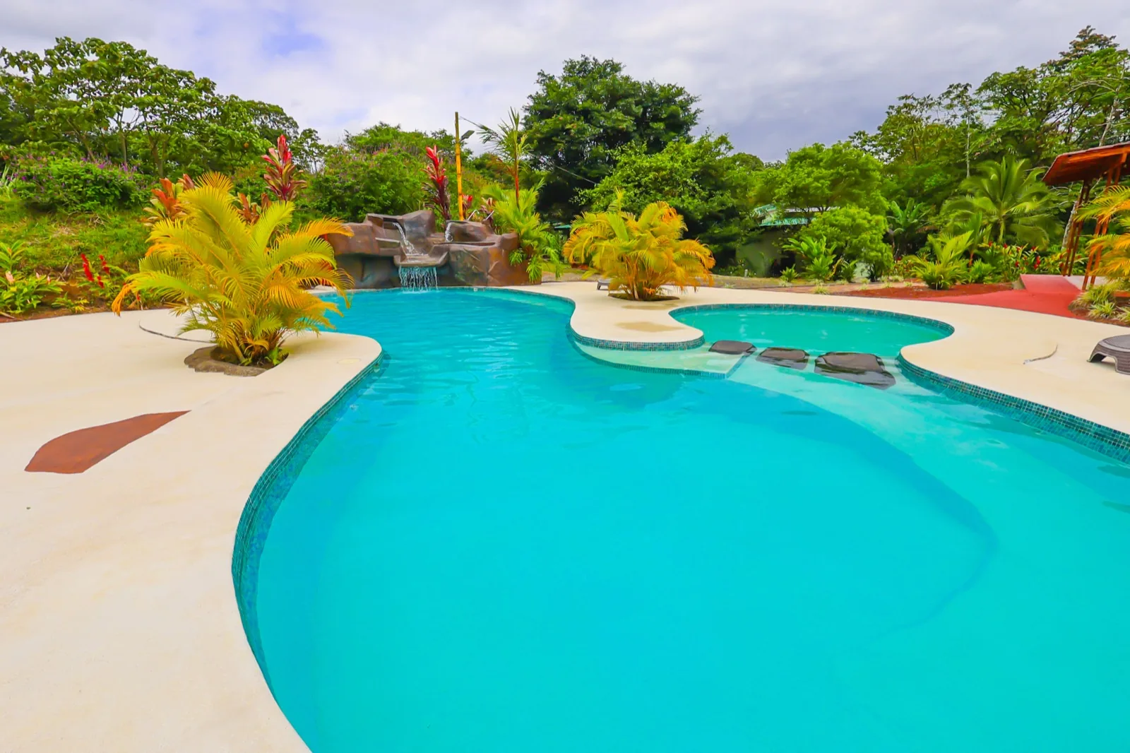 Piscina principal y piscina infantil rodeadas de jardines tropicales