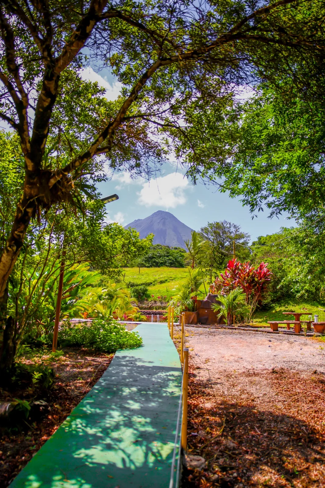 Volcán Arenal enmarcado por un sendero entre los jardines del hotel